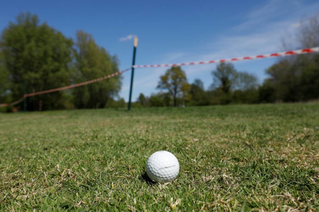 Dies würde zwei Strafschläge nach sich ziehen. Auspfosten sind befestigt und dürfen nicht bewegt werden. Entweder also die Spielrichtung ändern oder den Ball für unspielbar erklären, droppen und einen Strafschlag in Kauf nehmen.