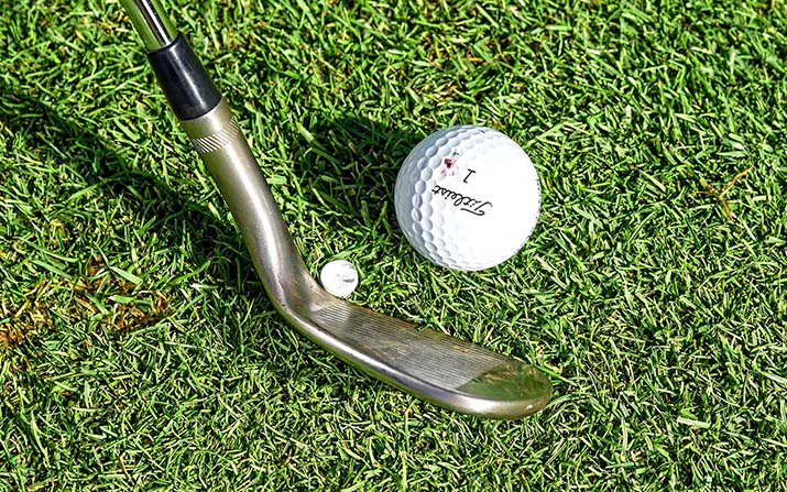 Golftraining Kurzspiel: Stecken Sie ein Tee knapp hinter und innen vom Ball in den Boden